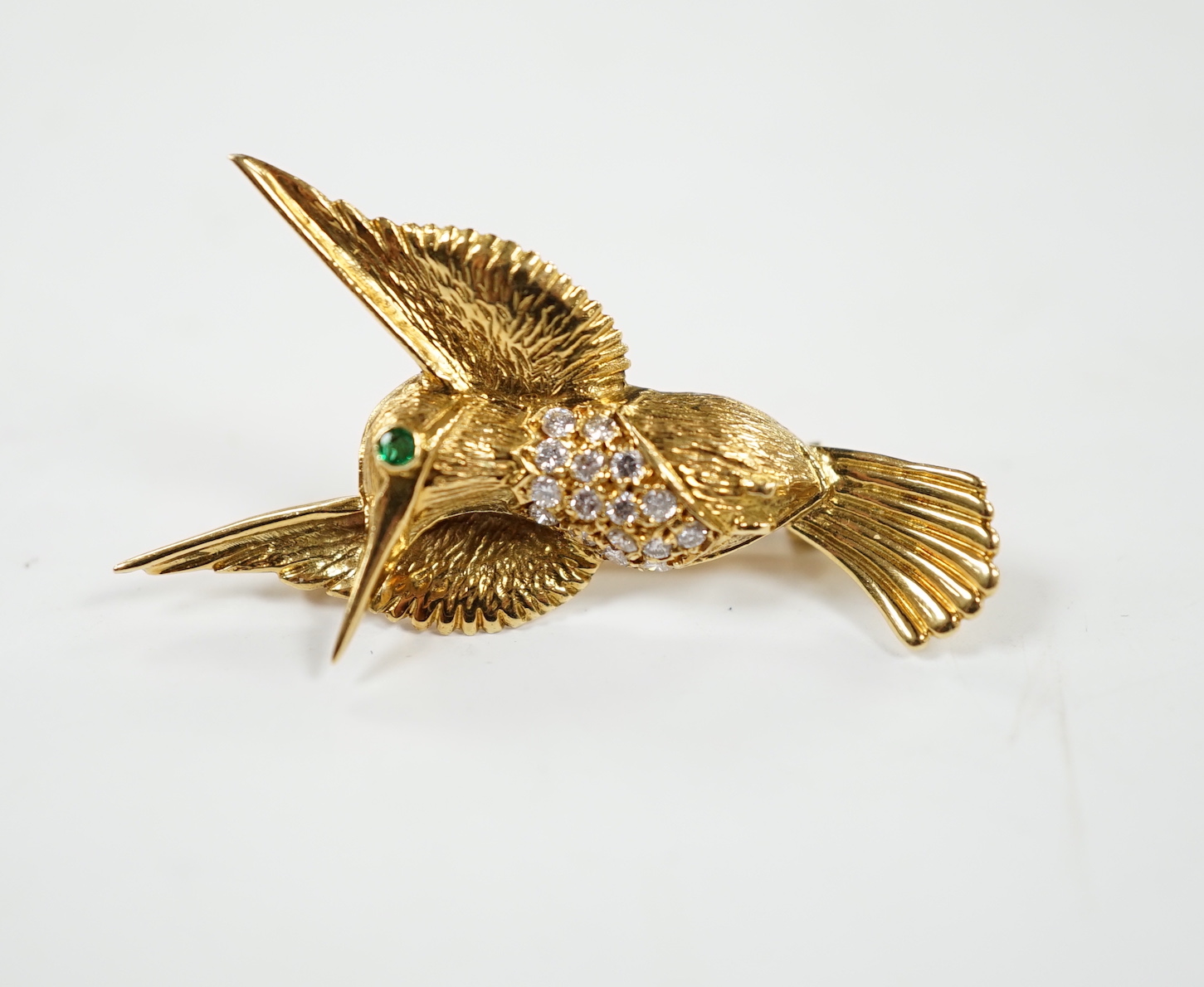 A modern 18ct and diamond cluster set kingfisher brooch, with emerald? set eye, 35mm, gross weight 5.3 grams.